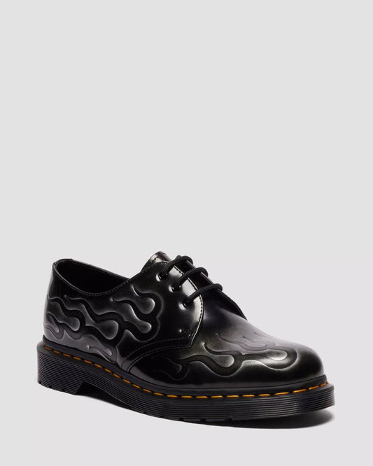 Black leather shoe with flame pattern on a light gray background