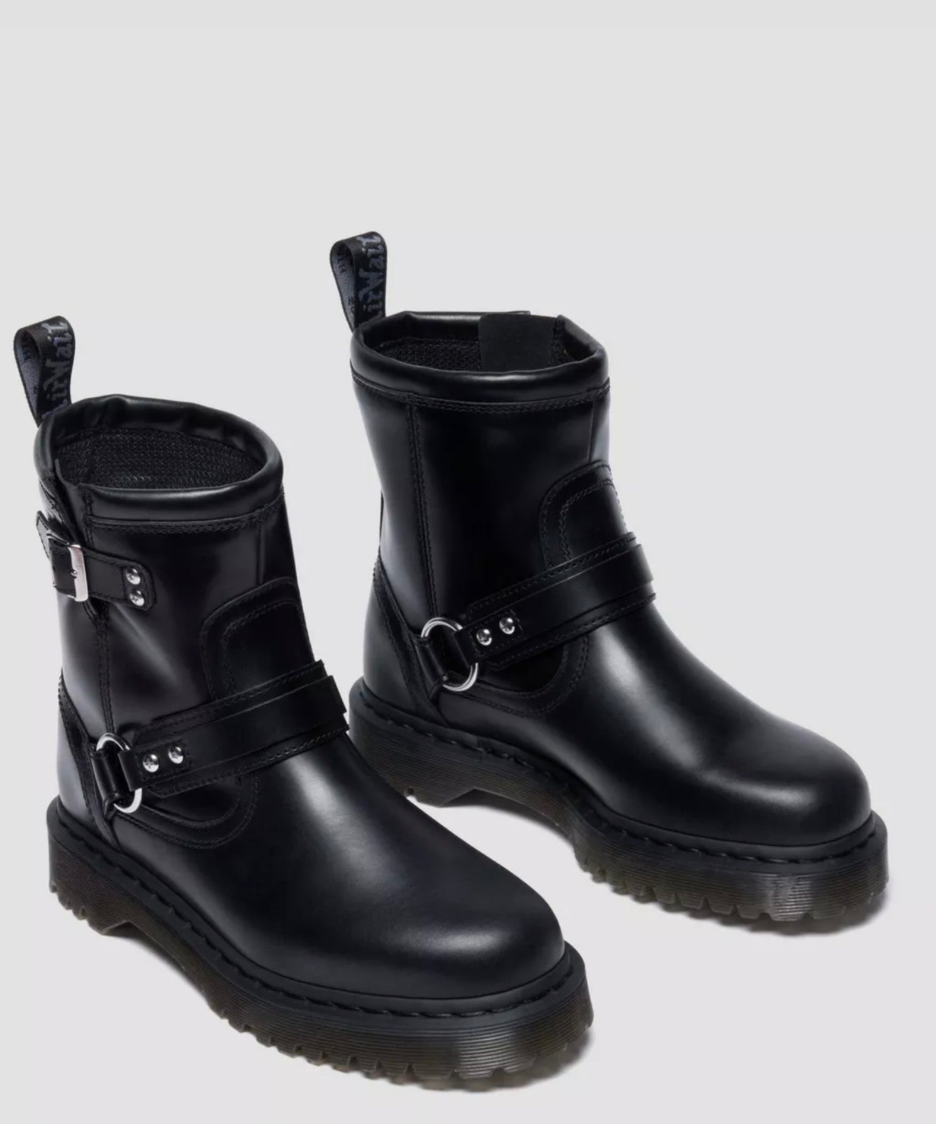 Pair of black leather boots with buckles on a light gray background