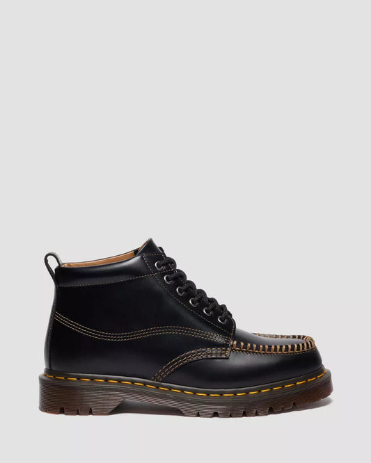 Black leather boot with yellow stitching on a light gray background