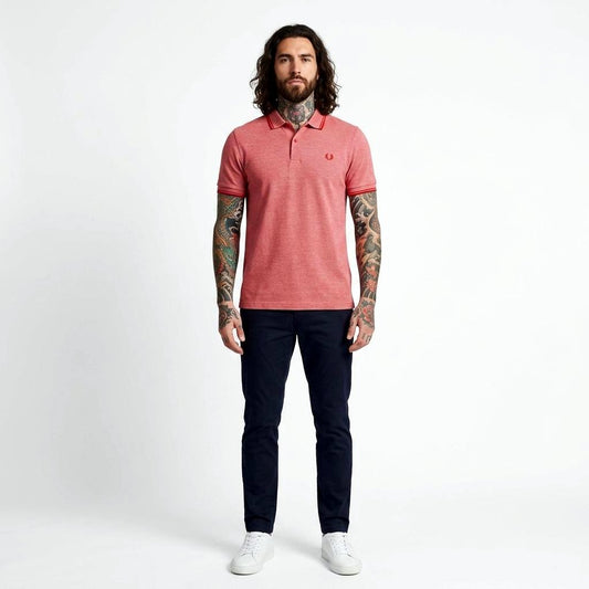 Man wearing a red Fred Perry twin-tipped polo shirt and dark pants on a white background