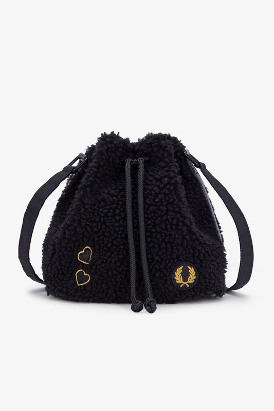 A black mini bucket-shaped handbag with a textured surface, featuring a drawstring closure and a branded tag on the lower right side.