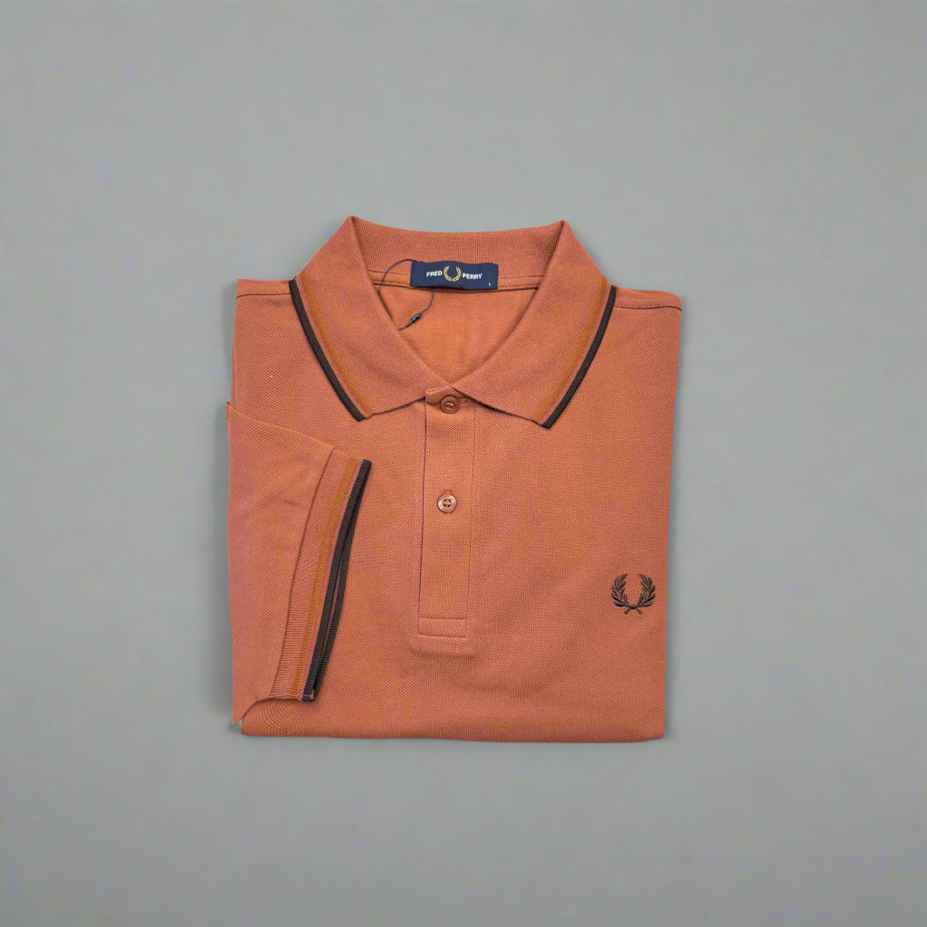 Folded orange polo shirt with black trim on a white background