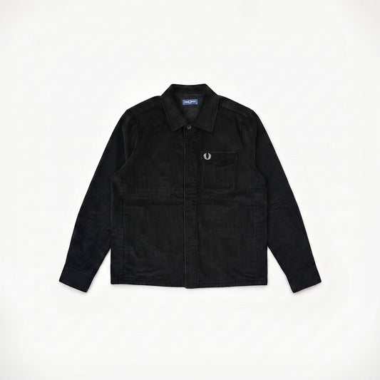 A black corduroy button-up shirt jacket with a chest pocket and a small embroidered logo, laid flat on a white background.
