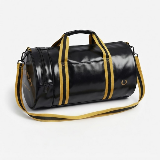 A black vinyl duffel bag with gold trim, featuring dual top handles, a detachable gold-and-black shoulder strap, and gold branding details on a light gray background.