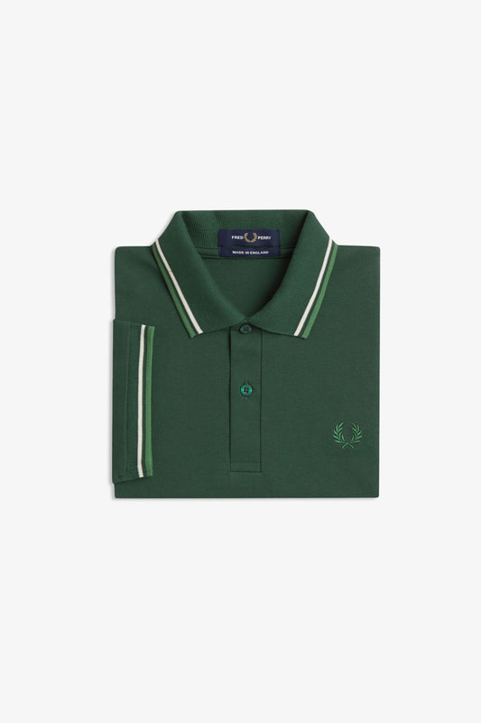 A folded dark green polo shirt with white and light green striped trim on the collar and sleeve cuff, featuring a small embroidered logo on the chest, set against a plain white background.
