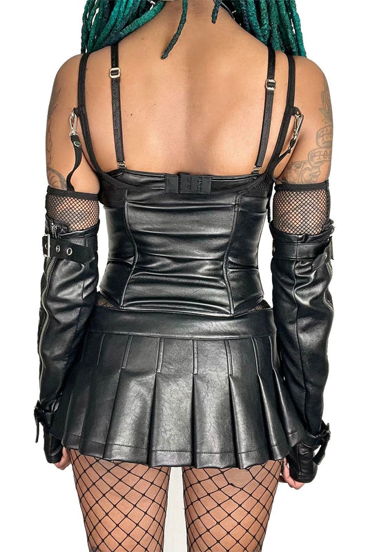Person wearing a lip service black leather outfit with a pleated skirt on a white background