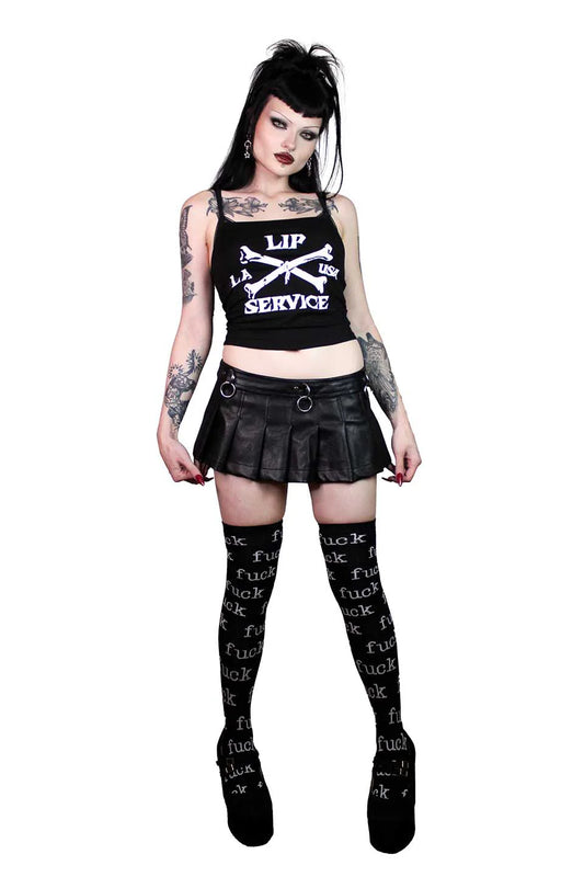 Person wearing a lip service black tank top with text, black skirt, and black stockings with text on a white background