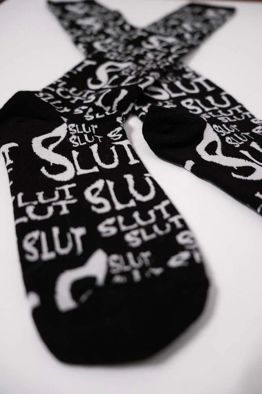 Black lip service socks with 'SLUT' printed in white on a white background