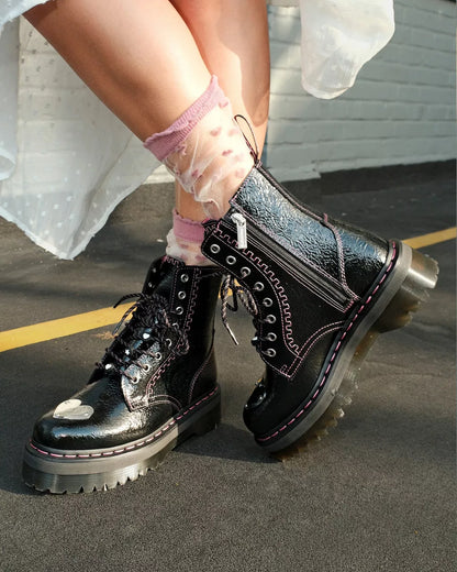 Black leather boots with glossy finish worn by a person on a concrete surface.