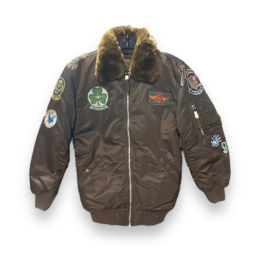 A youth-sized brown leather jacket with a fur lining at the collar, featuring various embroidered patches including a badge with a shamrock, an eagle, and other military-style insignia, as well as a 'Maverick' label on the back.
