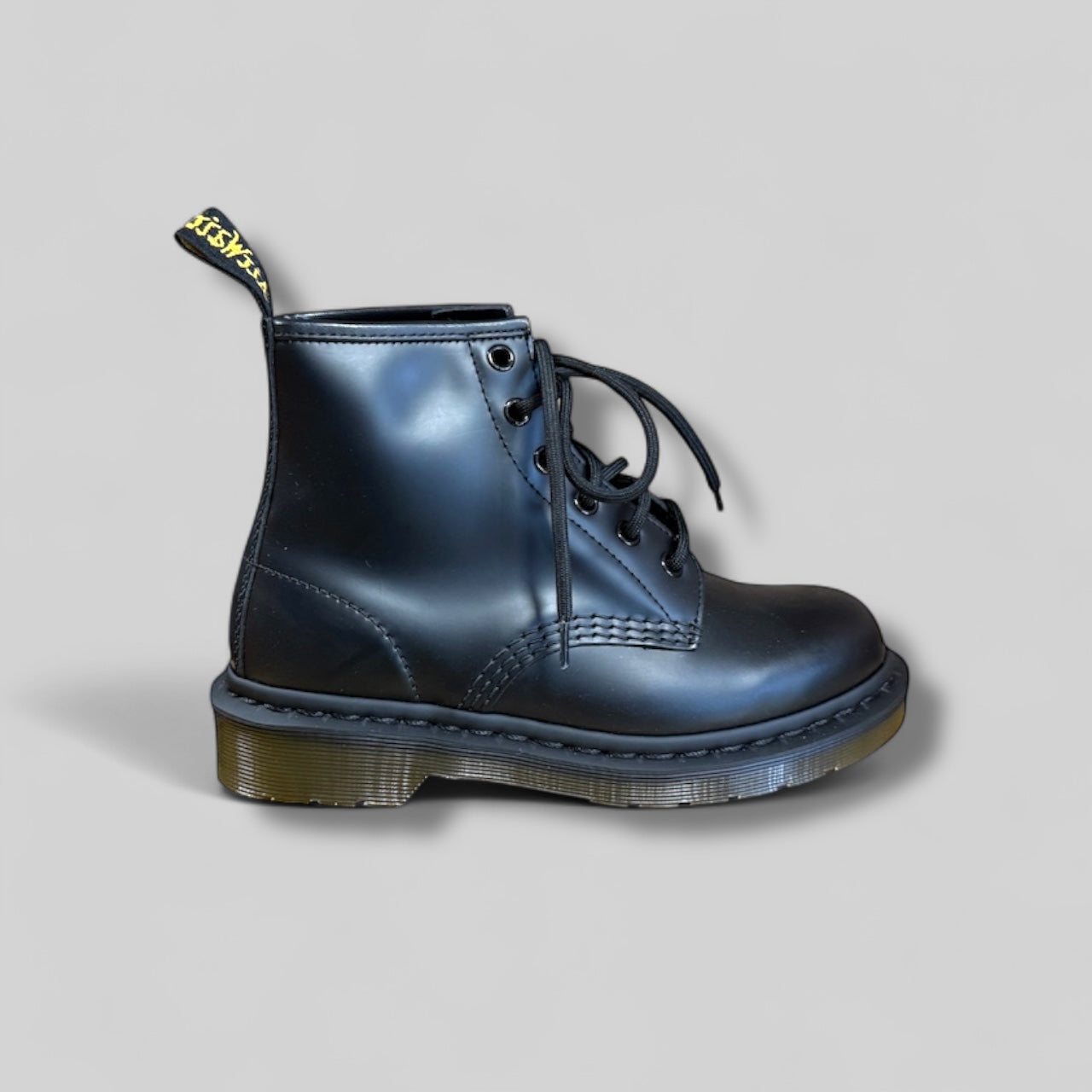 Black leather boot with yellow logo on a gray background