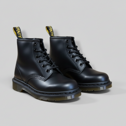 Pair of black leather boots with yellow accents on a light gray background