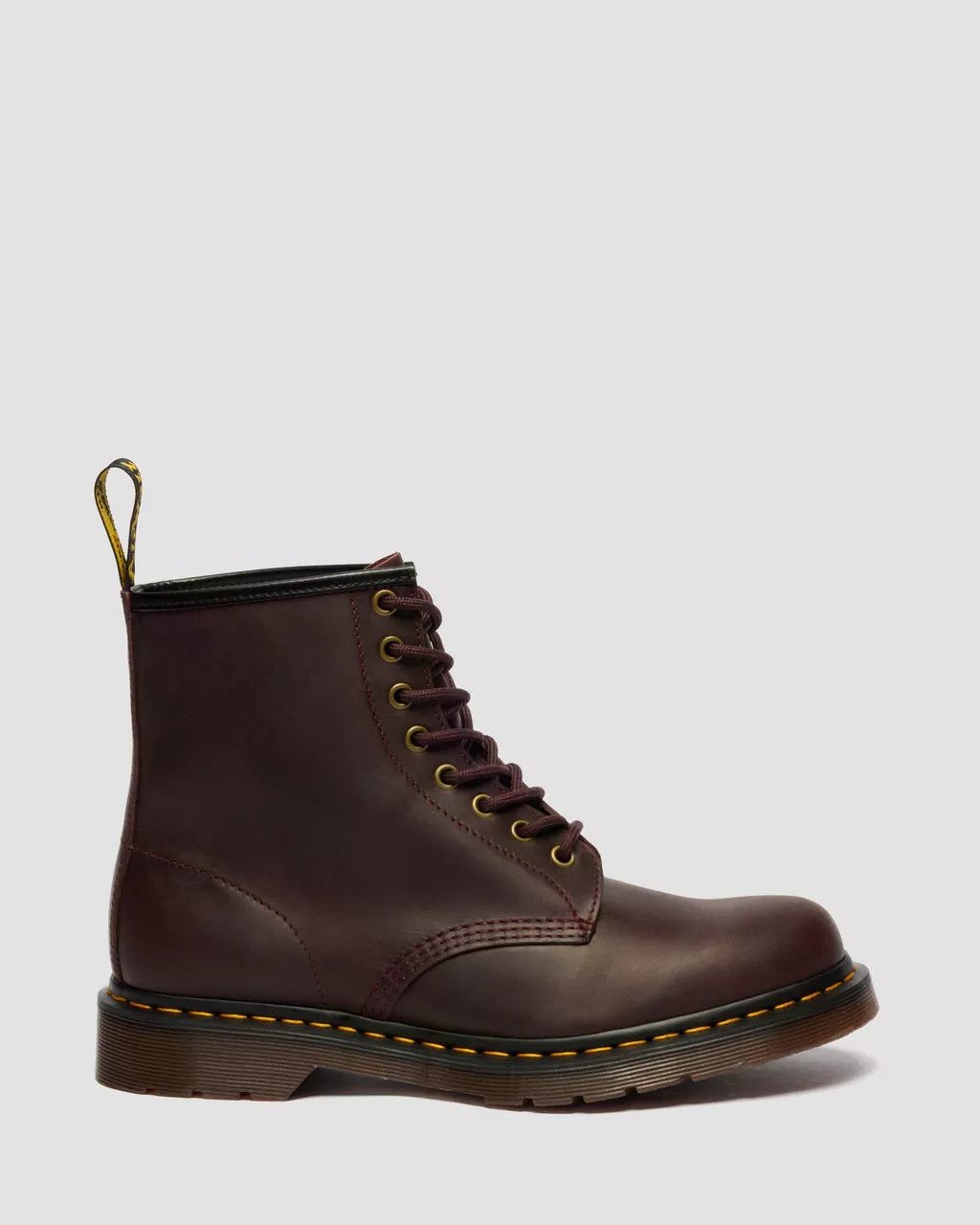 Brown leather boot with yellow stitching on a light gray background