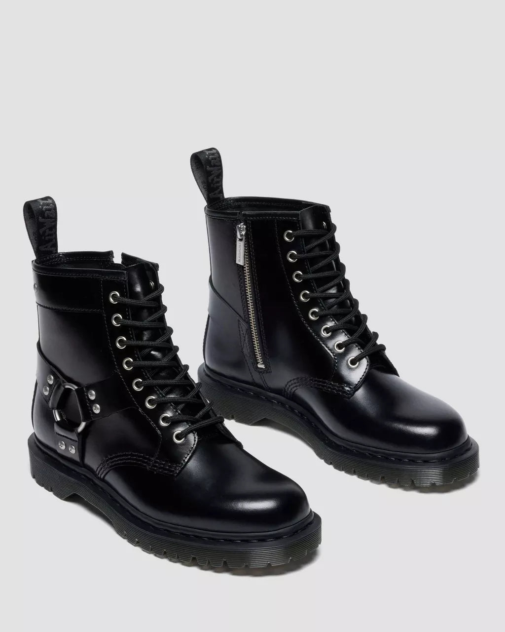 Pair of black leather boots with zippers on a light gray background