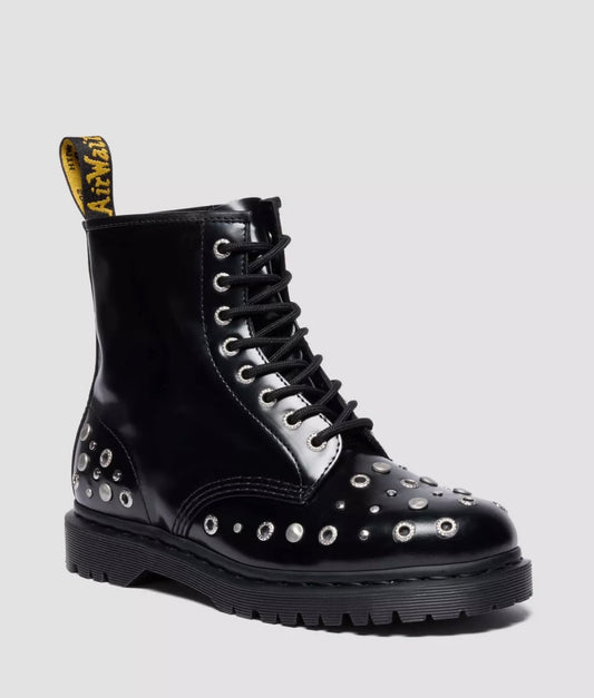 Black leather boot with studs and a white sole on a light gray background