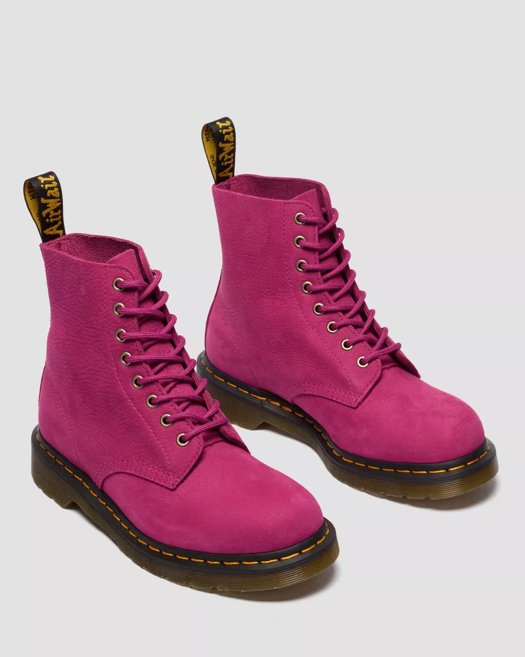 Pair of pink boots with black soles on a light gray background