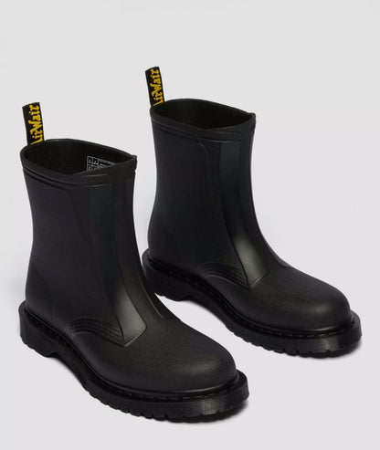 Pair of black rubber boots with yellow labels on a light gray background