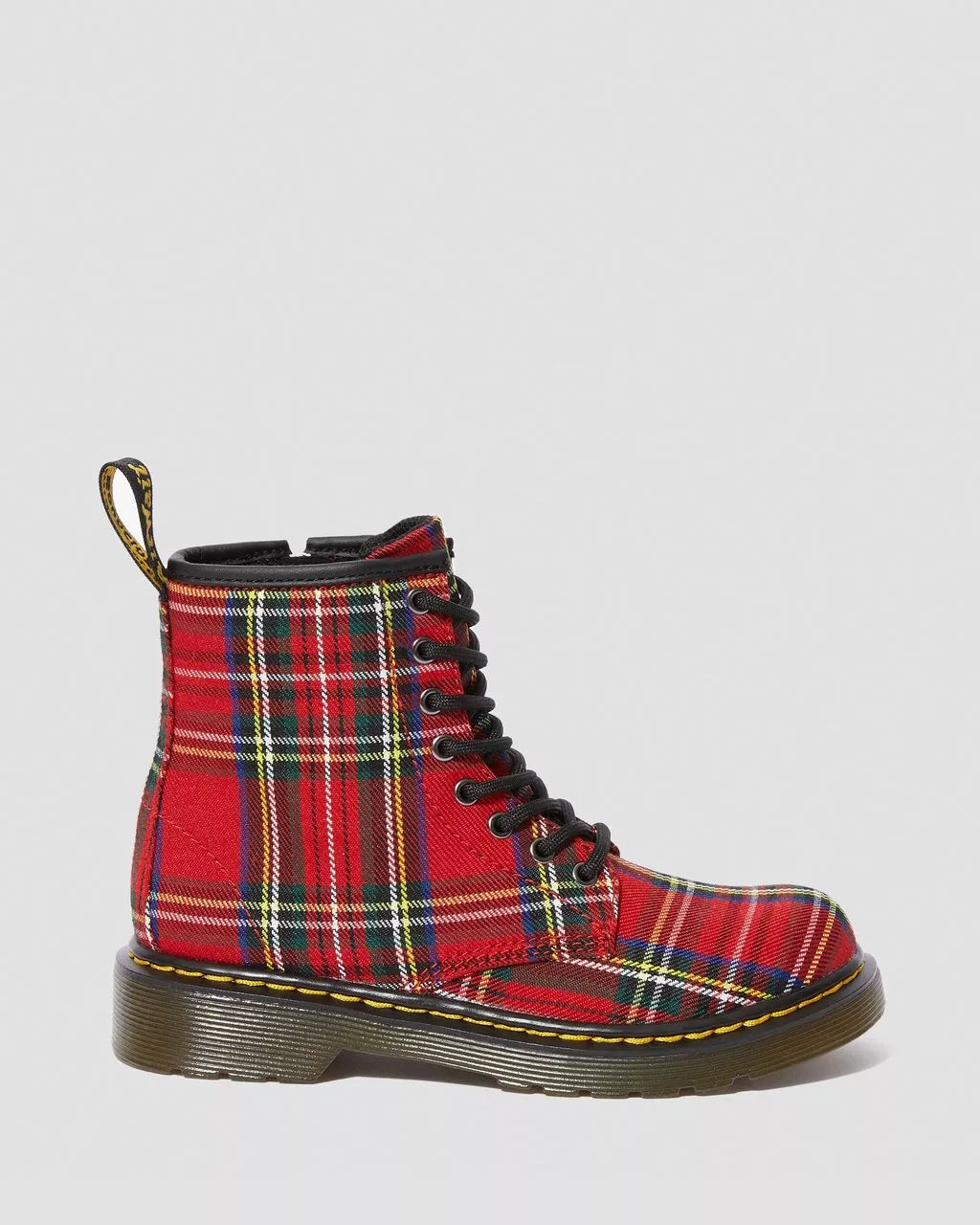 A red and green plaid junior boot with black laces and a yellow stitch, designed by Dr. Martens.