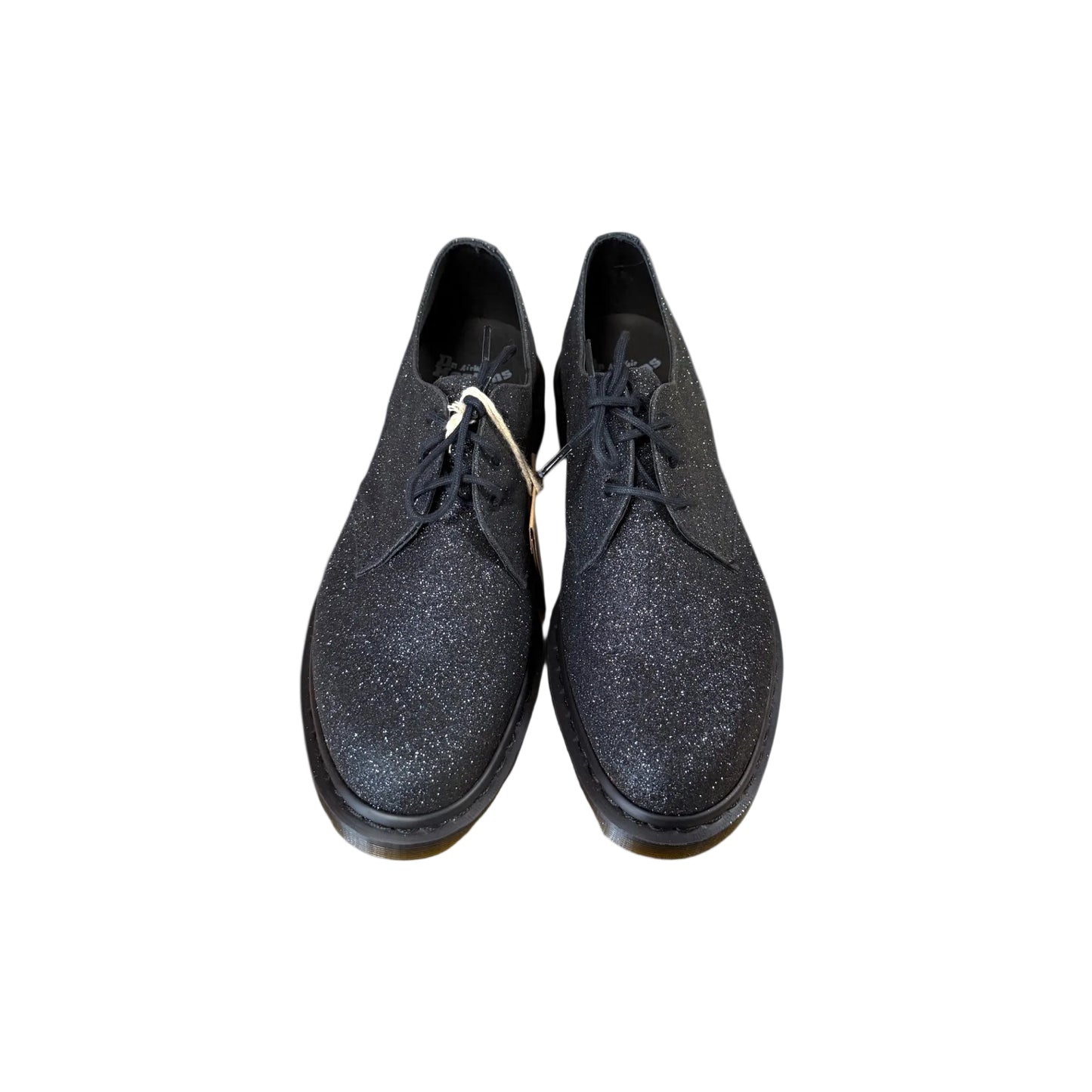 Pair of black glittery shoes on a light gray background