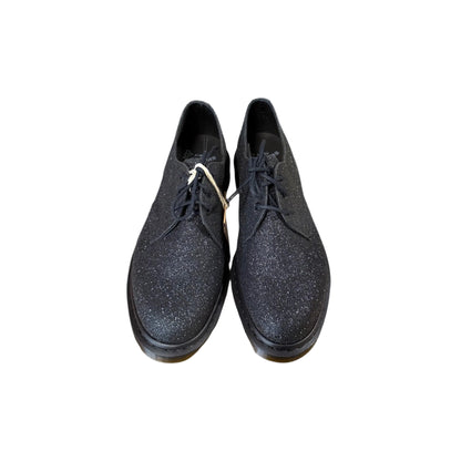 Pair of black glittery shoes on a light gray background