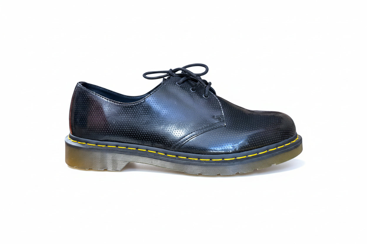 Shiny black shoe with yellow stitching on a white background