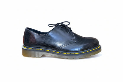 Shiny black shoe with yellow stitching on a white background