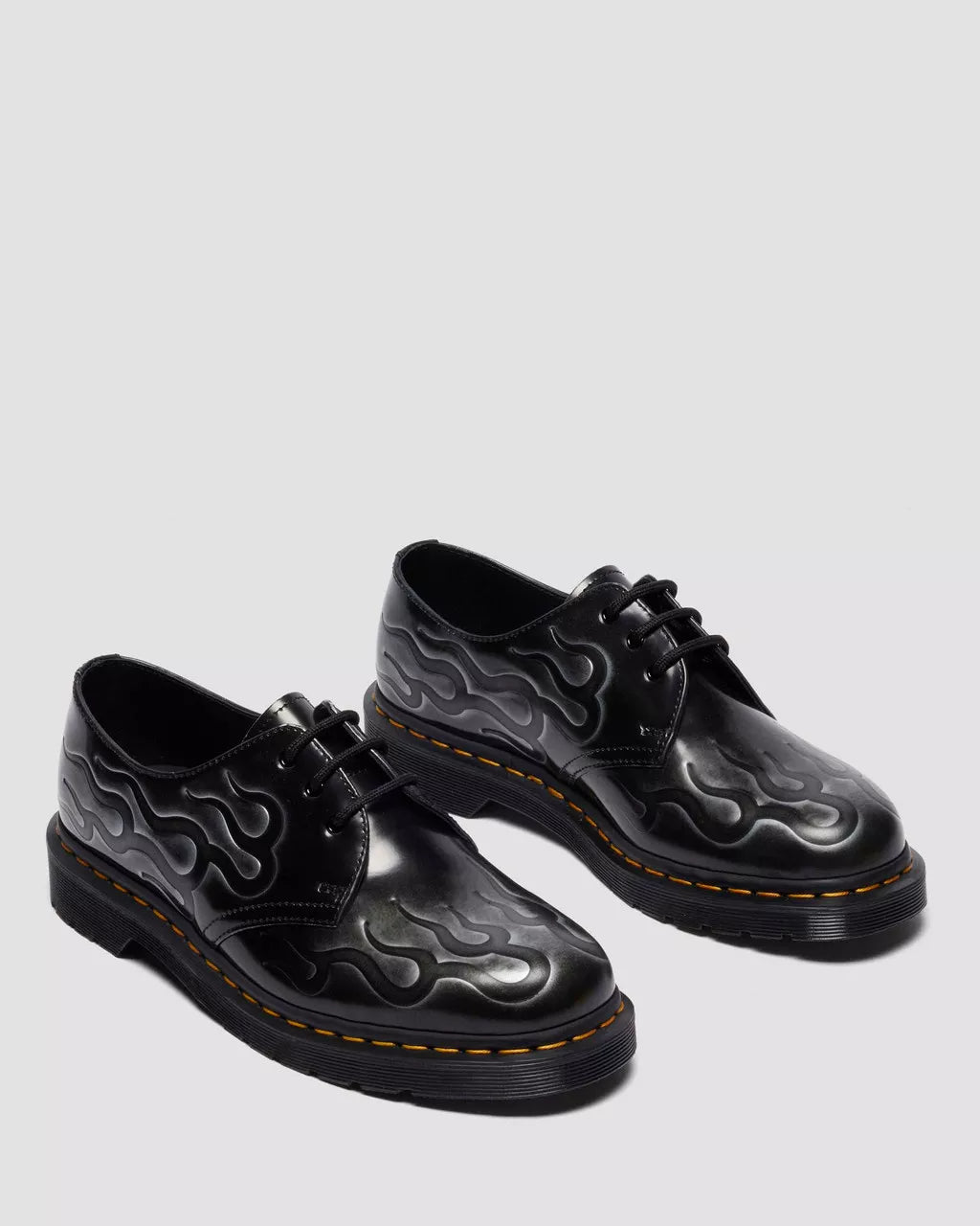 Black leather shoes with flame pattern on a light gray background
