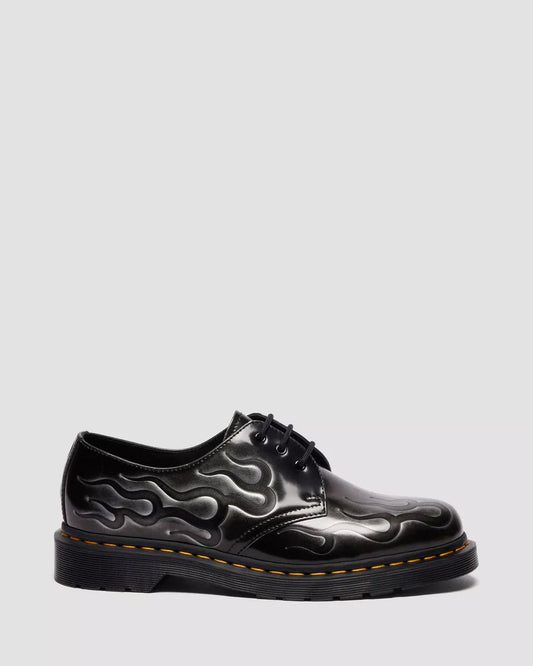 Black leather shoe with flame design on a gray background