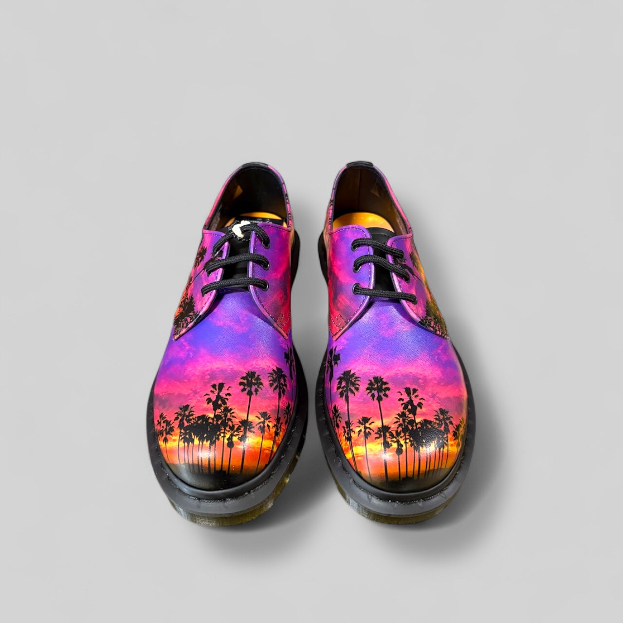Shoes with a colorful palm tree and sunset design on a gray background
