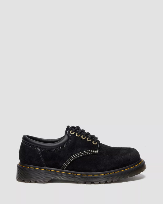 Black leather shoe with yellow stitching on a white background