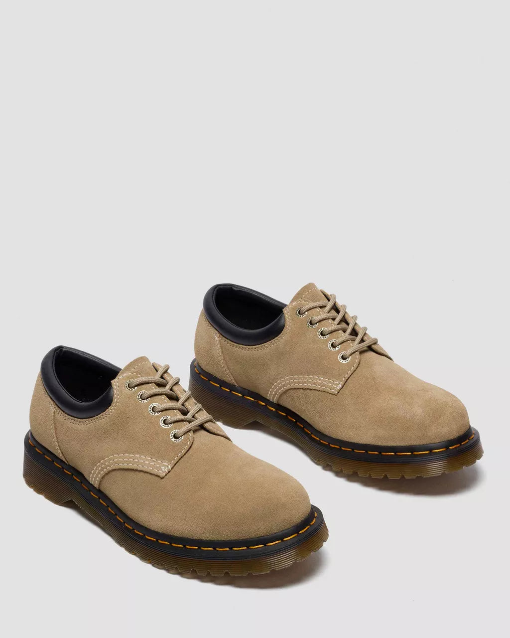 Pair of tan leather shoes with black soles on a light gray background