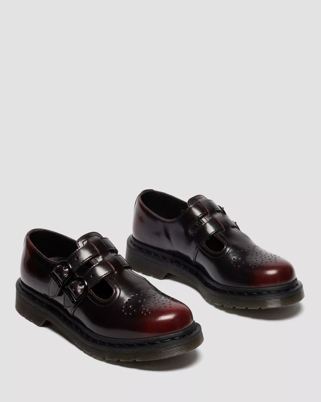 Pair of dark brown leather shoes with buckles on a light gray background