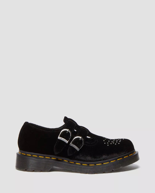 A pair of black vegan velvet Mary Jane shoes with two adjustable buckles and a grooved DMS sole with yellow welt stitching.