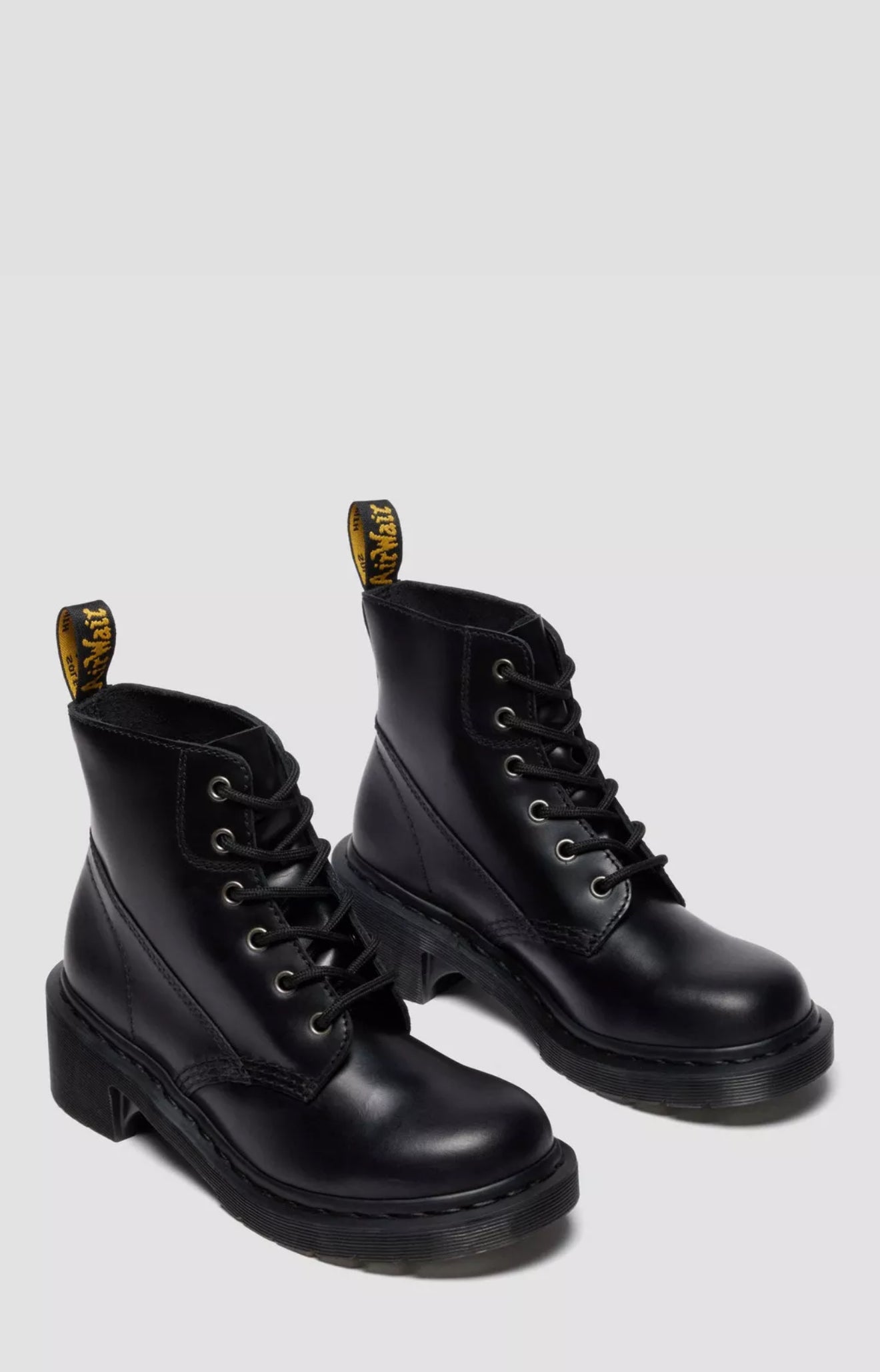 Pair of black leather boots with yellow accents on a white background