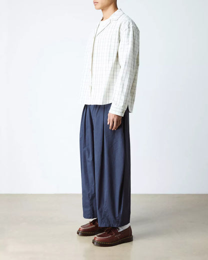 Person wearing a striped shirt and blue pants on a plain background