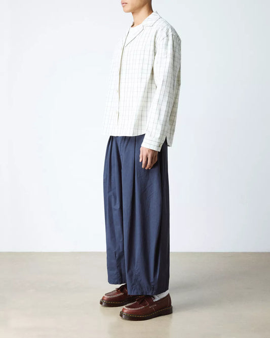 Person wearing a striped shirt and blue pants on a plain background