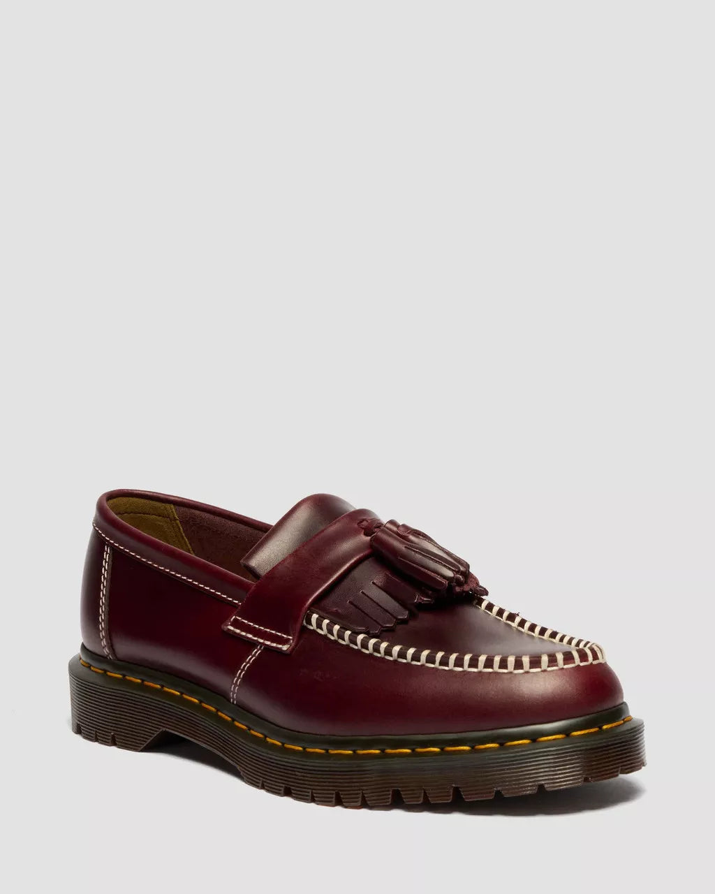 Brown loafers with tassels on a light gray background