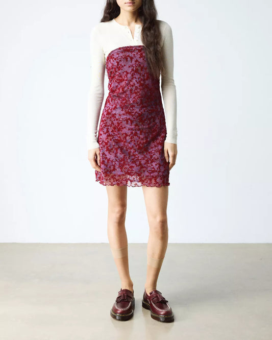 Person wearing a red floral dress with a plain background