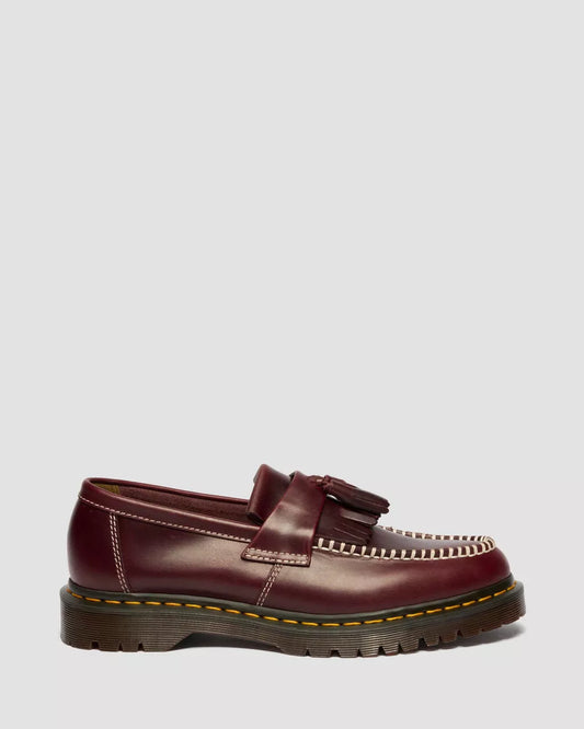 Brown leather loafer with tassels on a light gray background