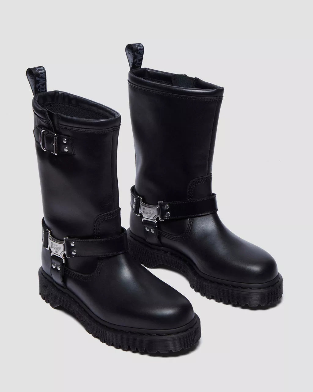 Pair of black leather boots with metal buckles on a light gray background