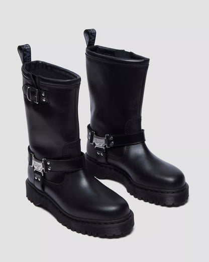 Pair of black leather boots with metal buckles on a light gray background