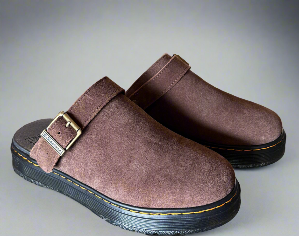 Pair of brown clogs with a strap on a gray background