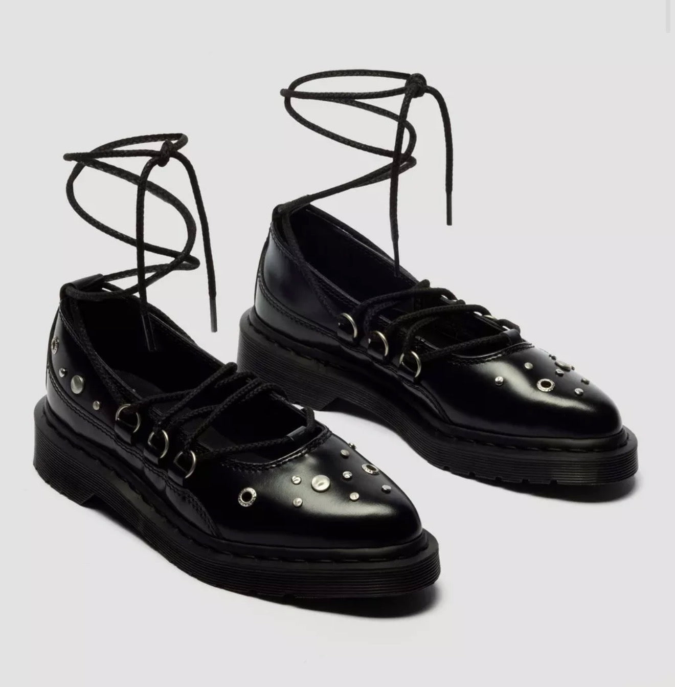 Black lace-up shoes with stud details on a light gray background