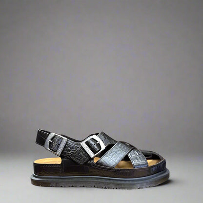 A dark brown fisherman sandal with crocodile pattern, featuring multiple straps and a flat sole.