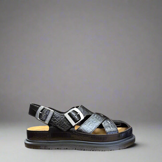 A dark brown fisherman sandal with crocodile pattern, featuring multiple straps and a flat sole.
