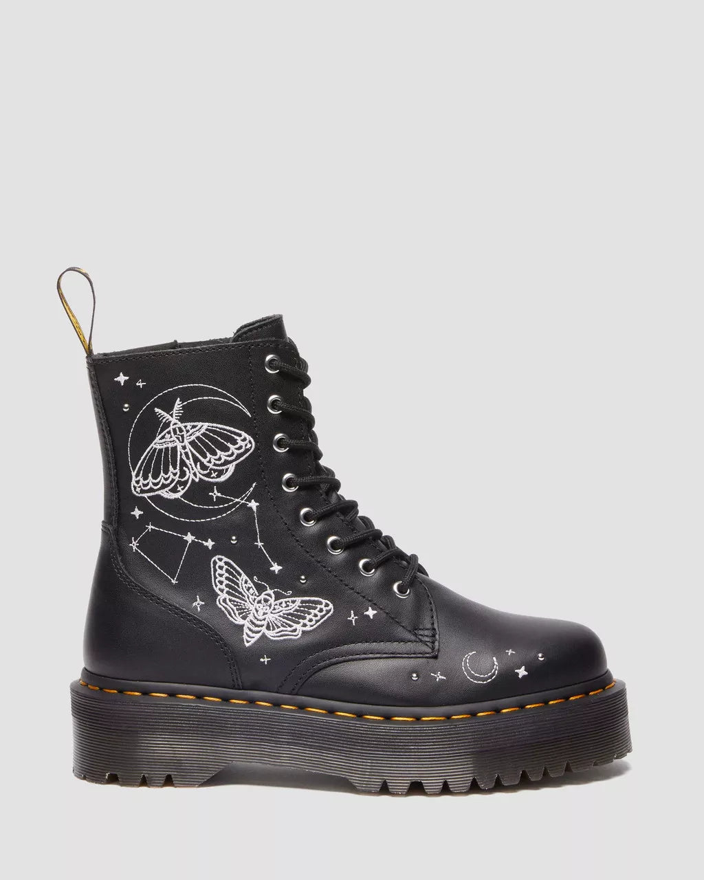 A pair of black Dr. Martens platform boots with embroidered celestial motifs, including stars and moths.