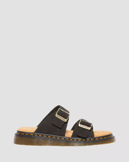 A pair of black suede slide sandals with buckle closures and a flat sole.