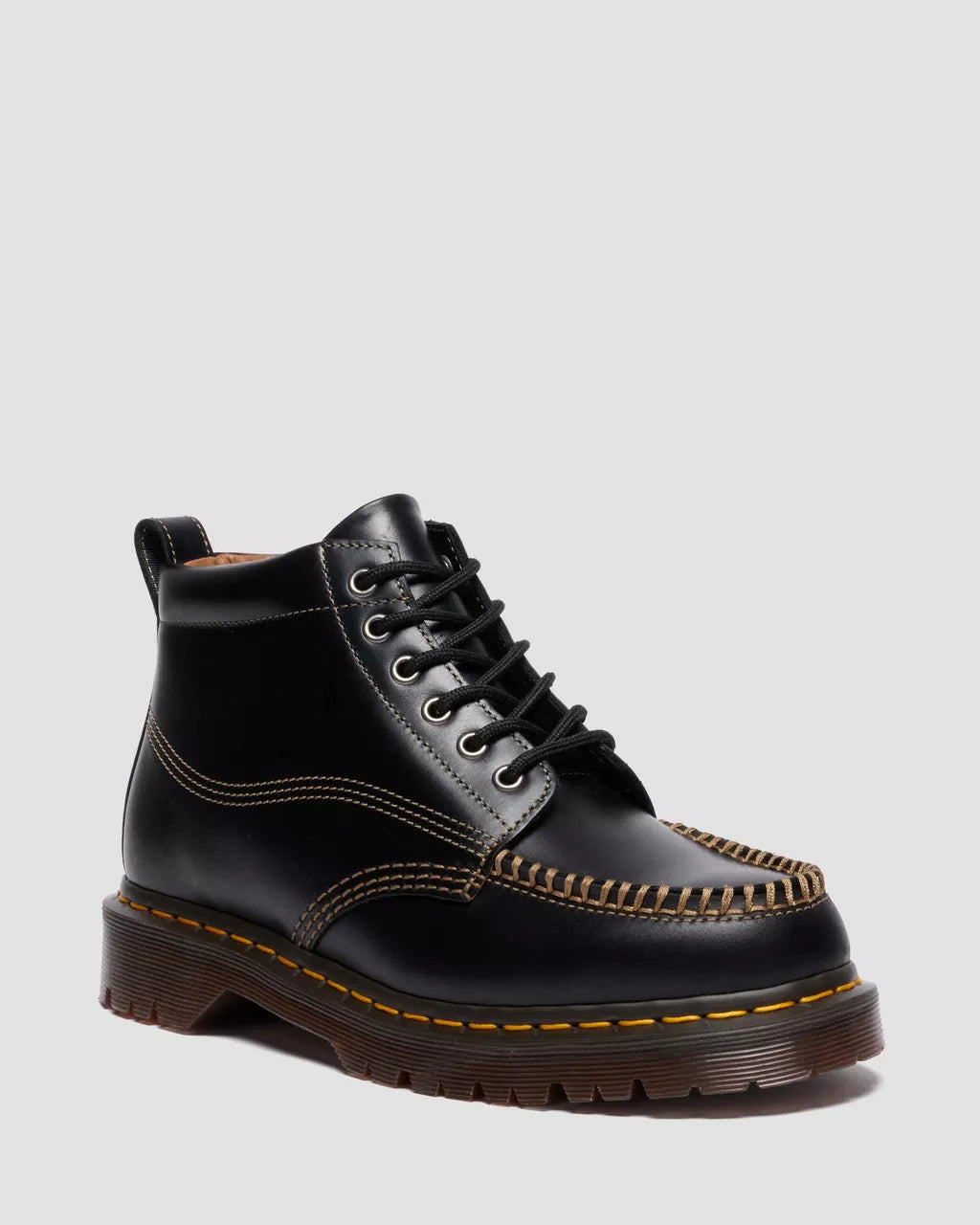 Black leather boot with brown stitching on a light gray background