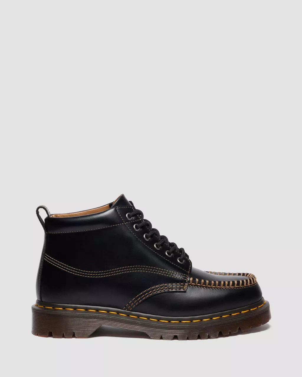 Black leather boot with yellow stitching on a light gray background