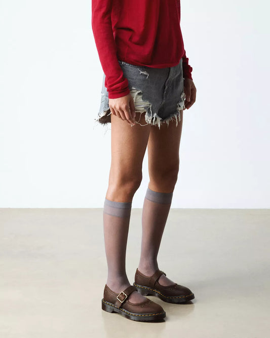 Person wearing a red sweater, denim shorts, and brown shoes on a white background
